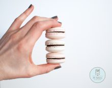 Pastel macarons with chocolate ganache being held in a hand