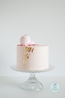 Pink cake topped with meringues and edible gold on the sides