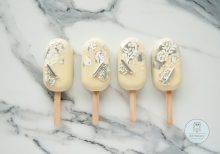 Four white cakesicles with flowers and silver decorations